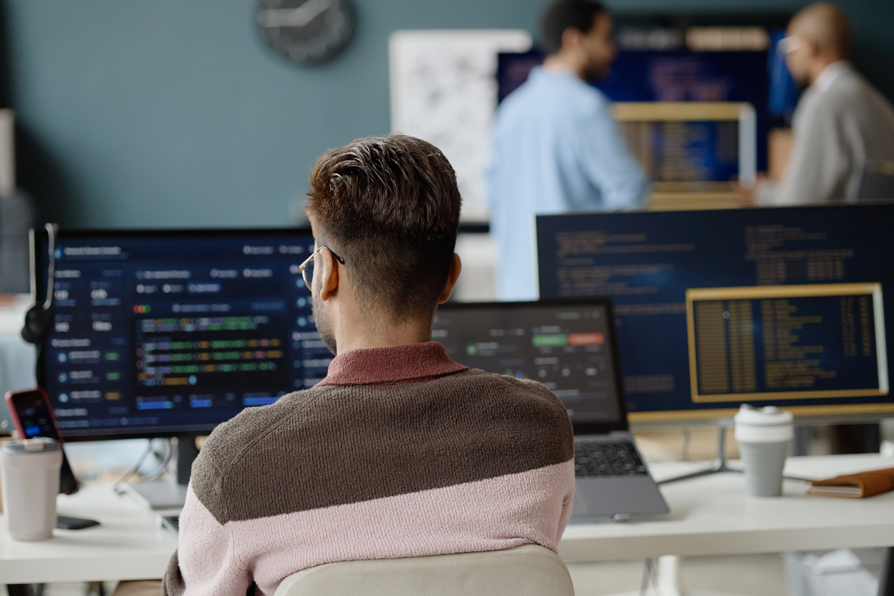 An engineer at a multi-monitor operations desk